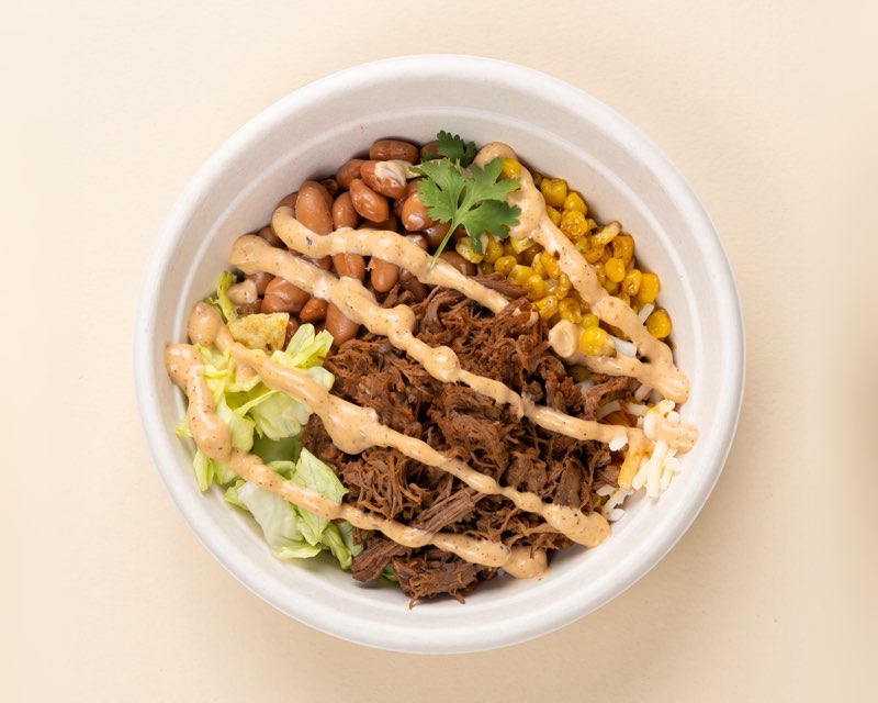 Burrito Loco bowl with pinto beans, beef barbacoa, charred corn, lettuce, cheese and a chipotle drizzle